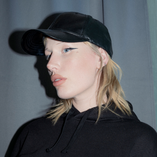 Kvinde i sort tøj der ser skråt ned mod kameraet