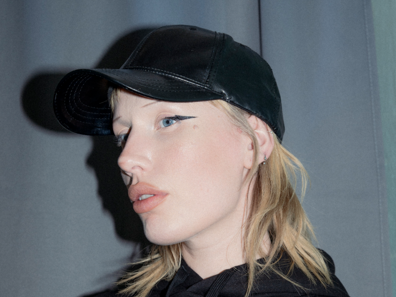 Kvinde i sort tøj der ser skråt ned mod kameraet