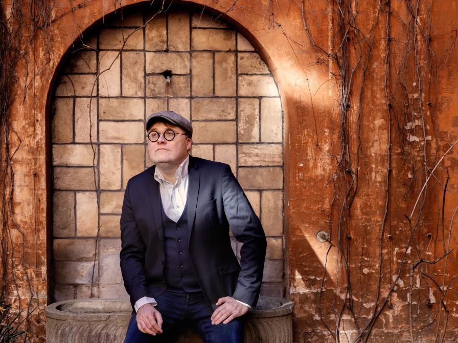 Man sidder ned og kigger forbi kameraet