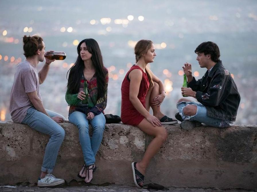 Fire unge mennesker drikker en øl og nyder udsigten